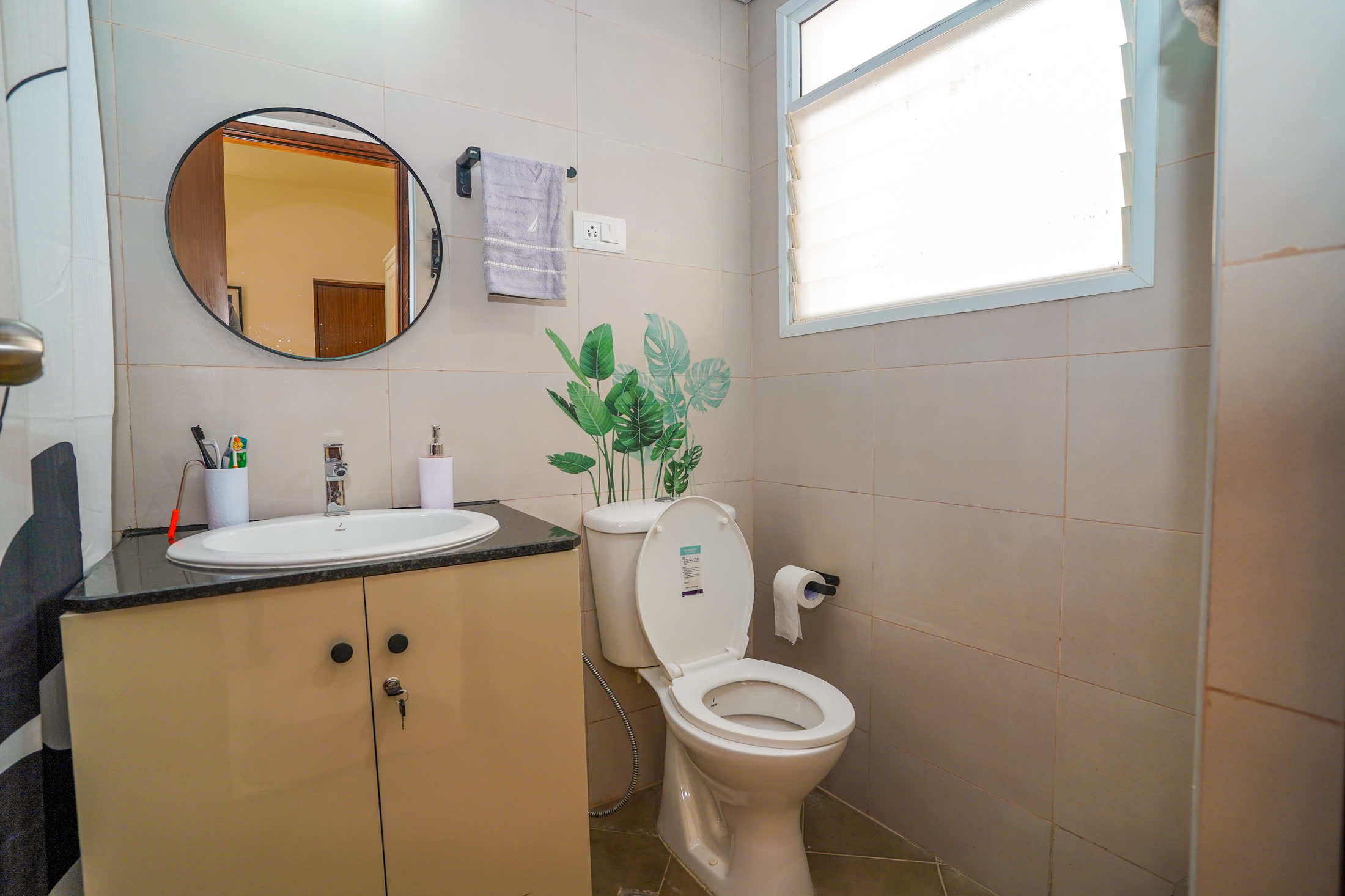Attached washroom with round mirror and vanity